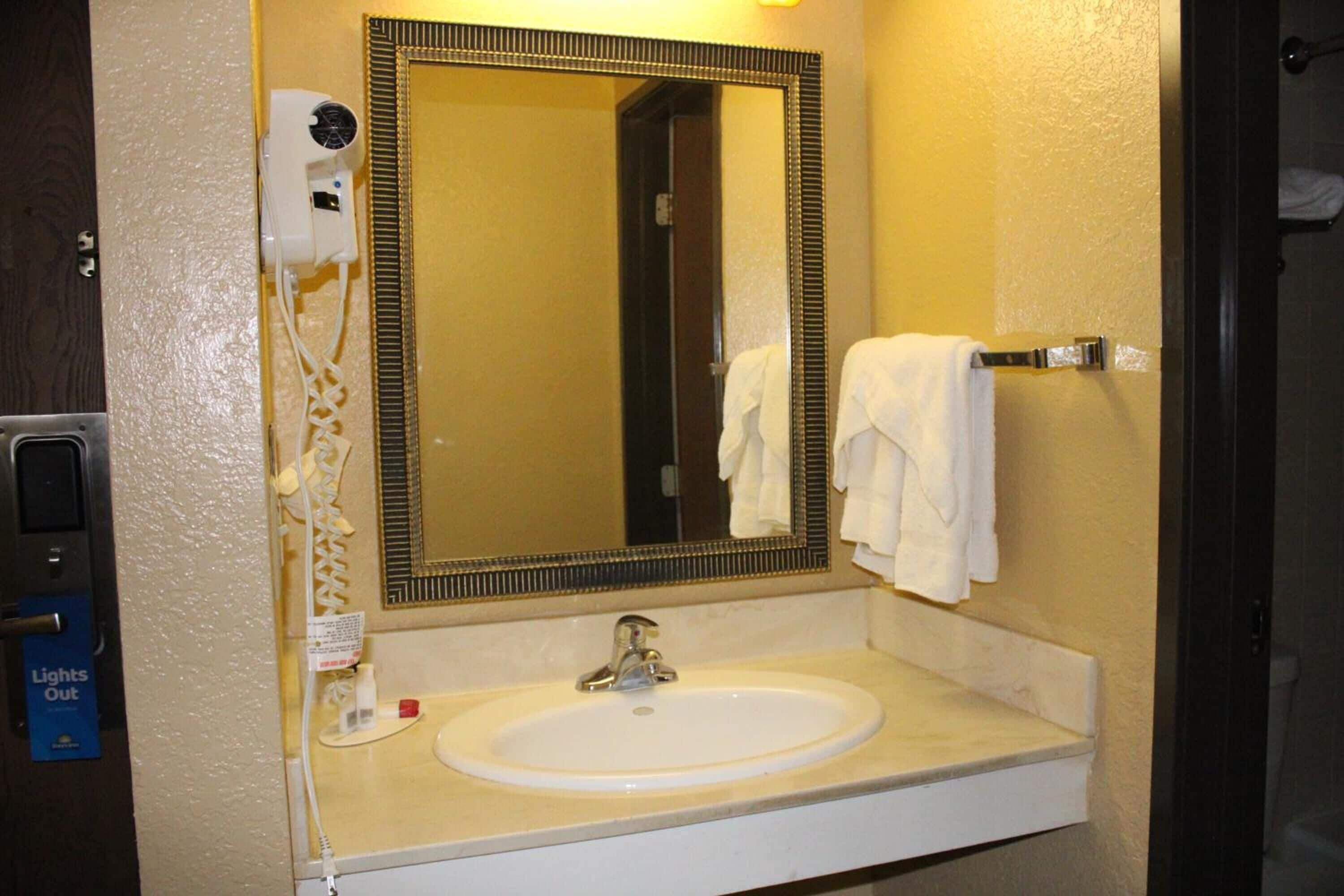 A bathroom with a white sink, a mirror, a towel rack, and a hairdryer.