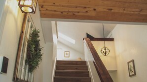 Eine Holztreppe mit Geländer, einer hängenden Pflanze und einer Wandleuchte.