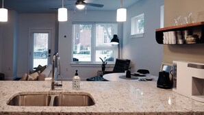 A kitchen with a granite countertop, stainless steel sink, ceiling fan, and a window with blinds. - Modern Unit in Historic Old Manchester. (Richmond)