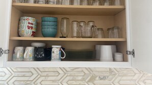 Un meuble de cuisine doté d’étagères où sont rangés divers bocaux en verre, des tasses à mesurer et des ustensiles de cuisine.