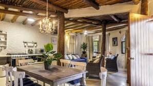 Uma área de refeições acolhedora com uma mesa e cadeiras de madeira, um candelabro e um vaso com planta.