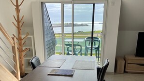 A dining area with a view of the sea, a wooden coat rack, and a staircase. - 3-star tourist DUPLEX SEA VIEW with Balcony & SWIMMING POOL (Penmarch)