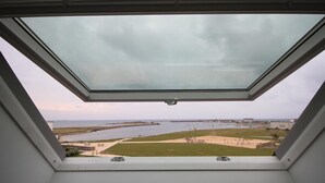 A skylight window with a view of a beach and water. - 3-star tourist DUPLEX SEA VIEW with Balcony & SWIMMING POOL (Penmarch)