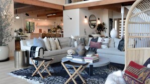 En rummelig opholdsstue med sofa, sofabord og et spiseområde i baggrunden.