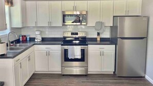 Una cocina moderna con armarios blancos, electrodomésticos de acero inoxidable y piso de madera.