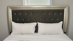 Una cama bien hecha con sábanas blancas y una toalla doblada.