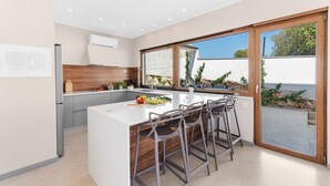 Une cuisine moderne dotée d’un îlot central, de tabourets de bar et offrant une vue sur un paysage rocheux grâce à de grandes fenêtres.