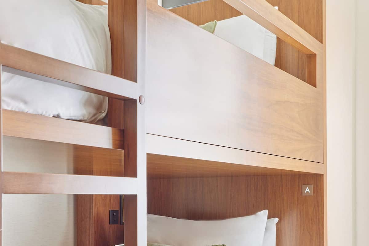 A bunk bed with wooden frames and white bedding.