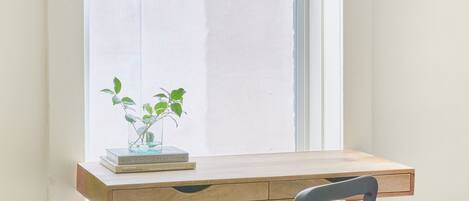 A room with a desk by a window, a chair, and a small plant on the desk.