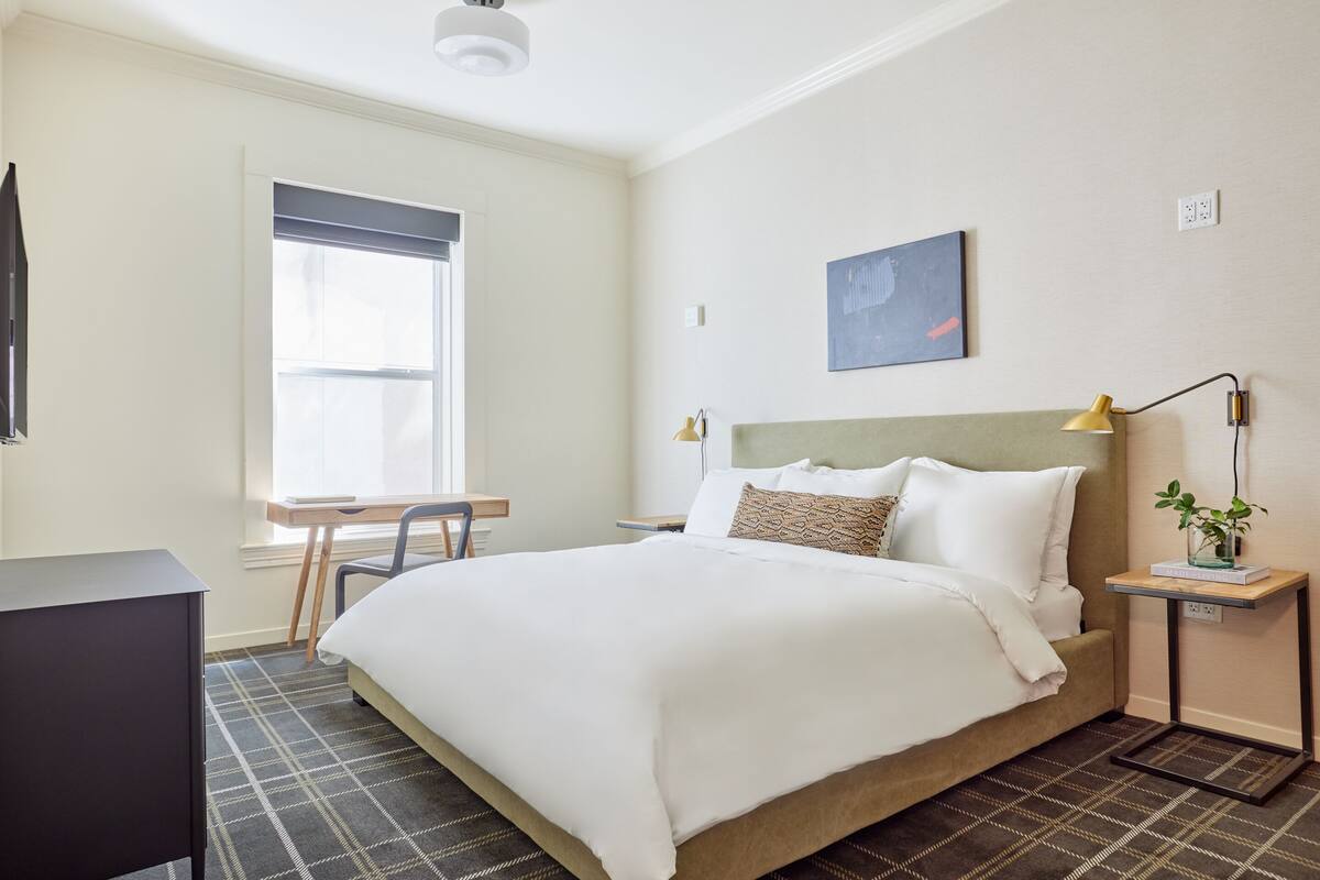 A neatly arranged bedroom with a bed, a desk, and a chair.