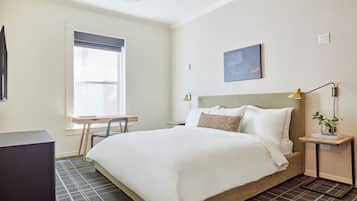 Ein ordentlich eingerichtetes Schlafzimmer mit einem Bett, einem Schreibtisch und einem Stuhl.