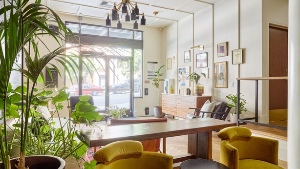 A modern interior with a wooden table, yellow chairs, and potted plants. - FOUND Hotel, San Francisco (San Francisco)