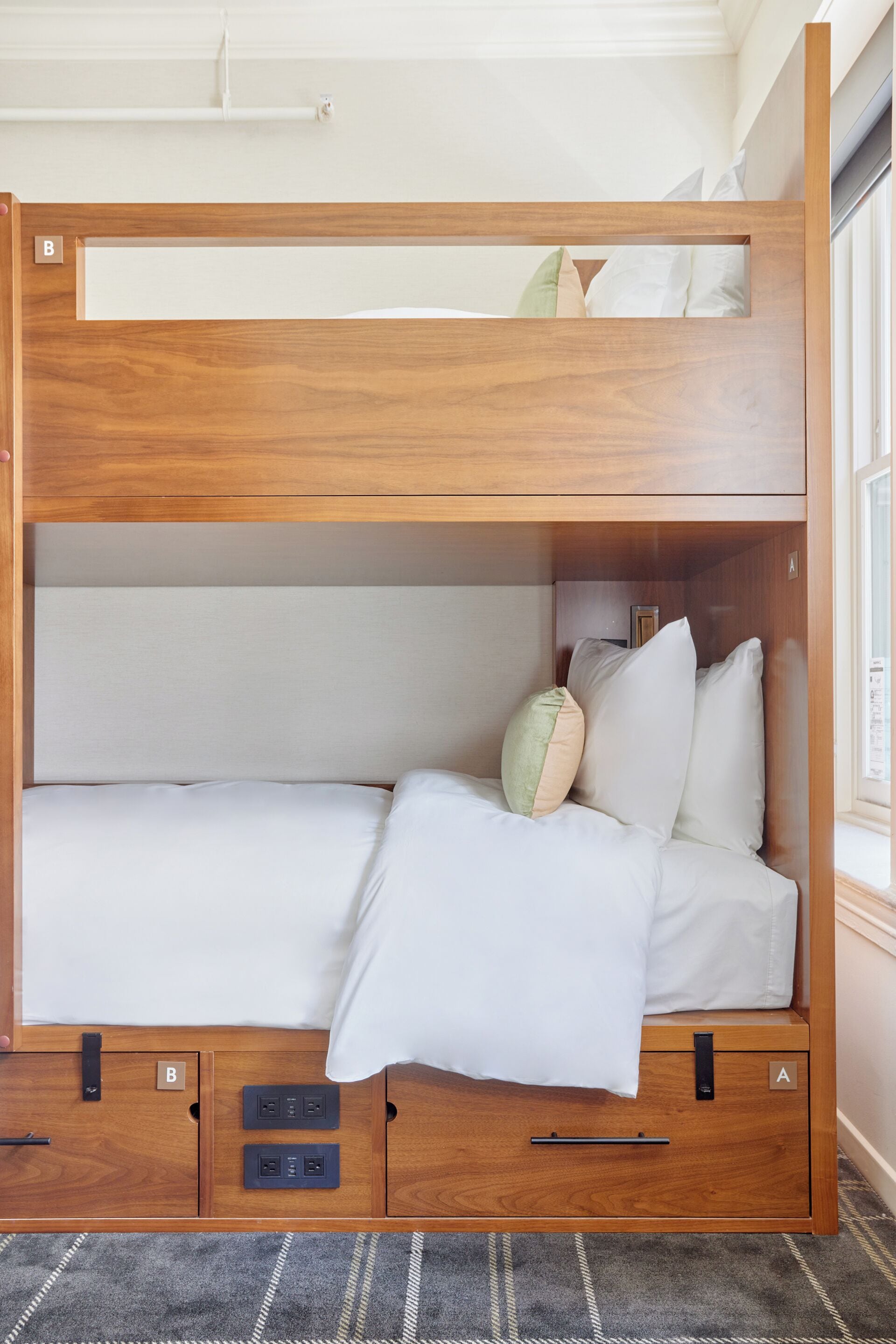 Una cama litera con estructura de madera, dos cajones y una ventana en la parte superior.
