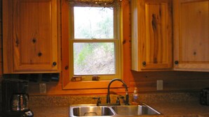 Eine Küche mit Holzausstattung, einem doppelten Spülbecken und einem Fenster mit Blick auf Bäume.