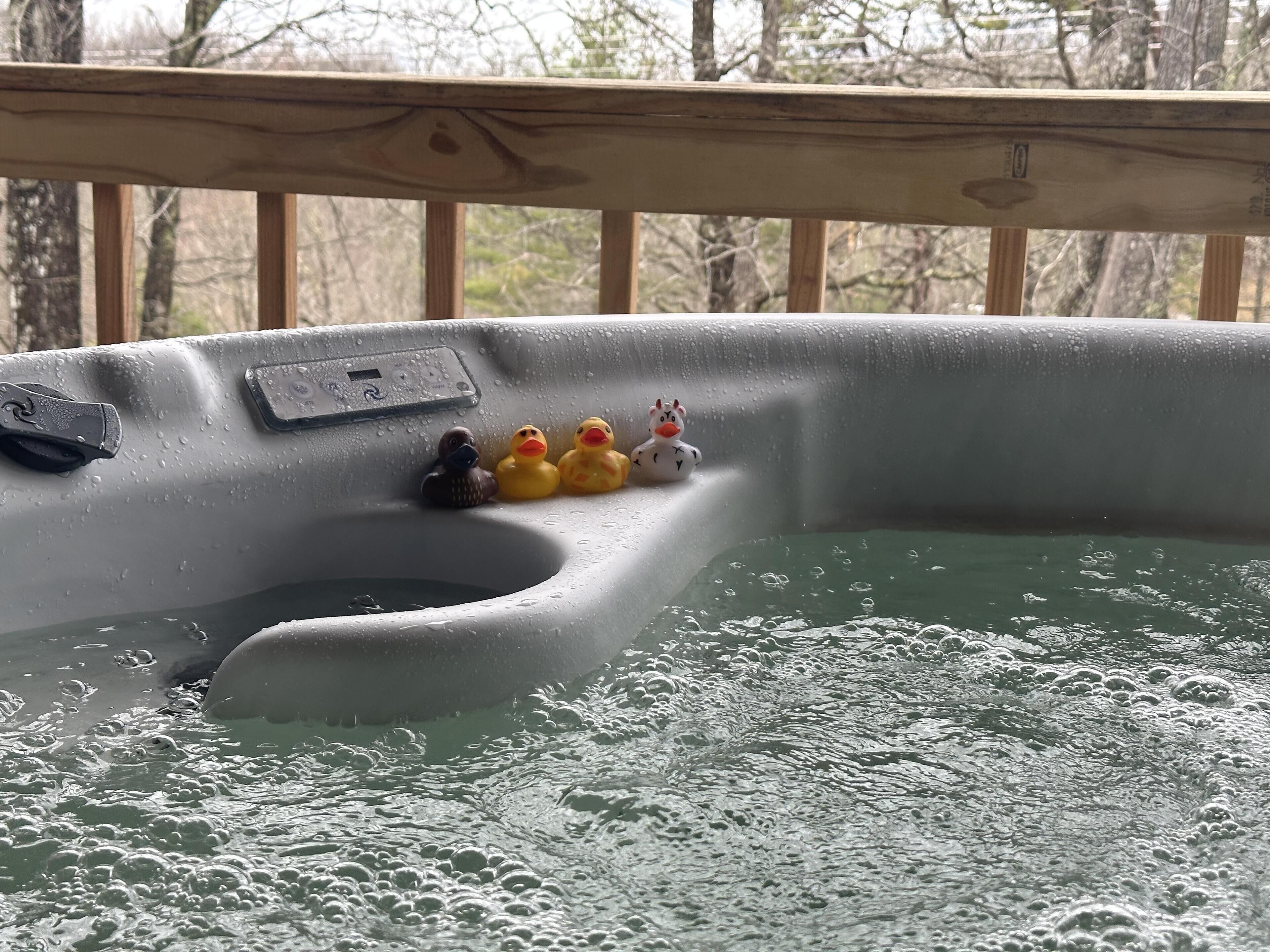 A hot tub with a wooden deck and a view of trees in the background.