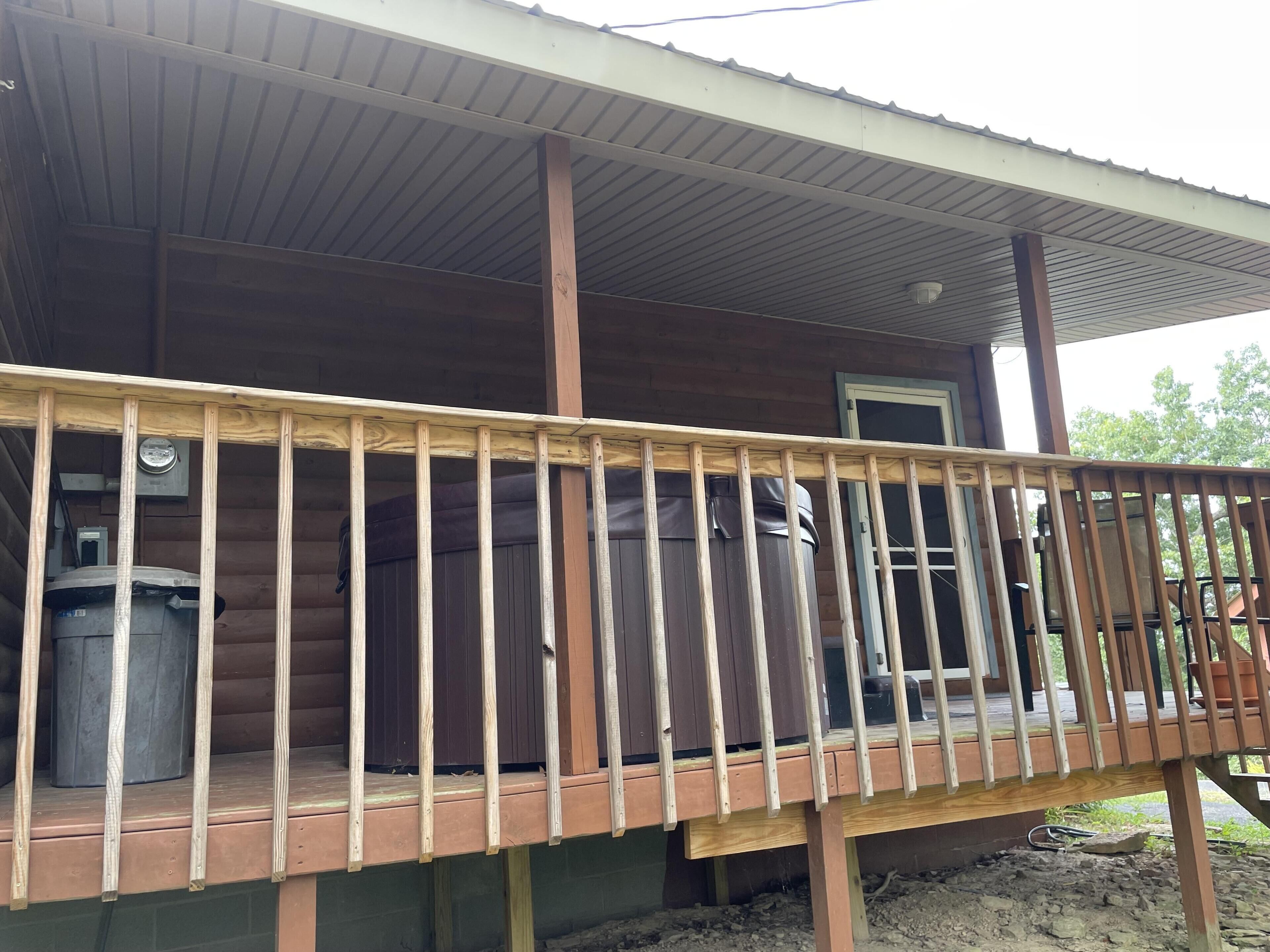 A wooden deck with a railing, a covered porch, and a window.