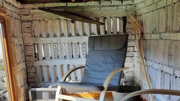 Una habitación acogedora con pared de piedra, techo de madera y un gran ventanal.