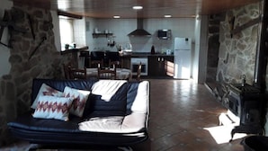 Una sala de estar acogedora con un sofá, una chimenea y una cocina al fondo.