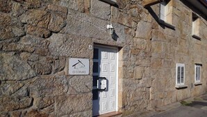 Un edificio de piedra con una puerta blanca, una pequeña señal con el símbolo de una mano y un farol sobre la puerta.
