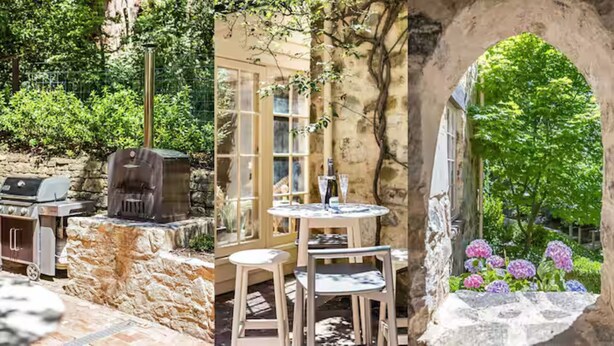 Une terrasse extérieure avec un mur en pierre, un barbecue et une table avec des chaises.