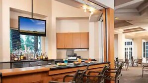 A bar area with a long counter, multiple chairs, and a television mounted on the wall.