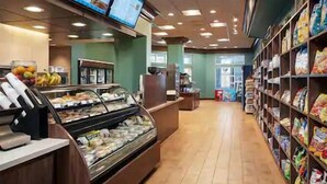 A bakery display case with various baked goods, a refrigerated display case with dairy products, and shelves stocked with packaged snacks.