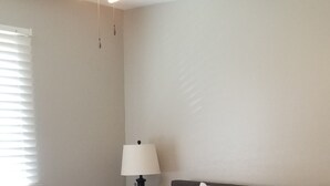 A bedroom with a bed, a nightstand, a lamp, and a ceiling fan.