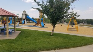 A playground with slides, swings, and a covered seating area.