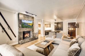 A modern living room with a fireplace, a flat-screen TV, and a sofa set.