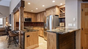 A spacious kitchen with wooden cabinets, a stainless steel refrigerator, and a granite countertop. - Managed by Park City Lodging-True Ski-In/Ski-Out to Park City Mountain Resort! (Park City)