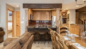 A kitchen with wooden cabinets, a bar area, and a dining table set for four. - Managed by Park City Lodging-True Ski-In/Ski-Out to Park City Mountain Resort! (Park City)