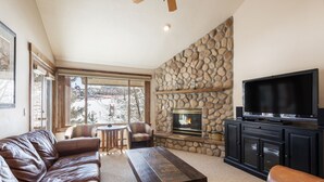 A cozy living room with a stone fireplace, leather sofa, and a flat-screen TV. - Managed by Park City Lodging-True Ski-In/Ski-Out to Park City Mountain Resort! (Park City)