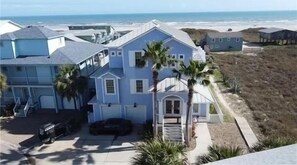 A two-story house with a garage, a driveway, and a view of the beach.