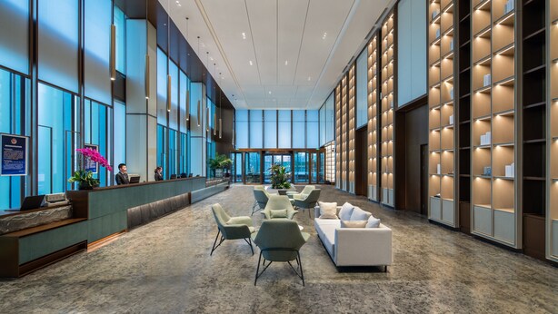 A spacious lobby with a reception desk, seating area, and a large bookshelf. - Somerset Daxing Beijing (Daxing)