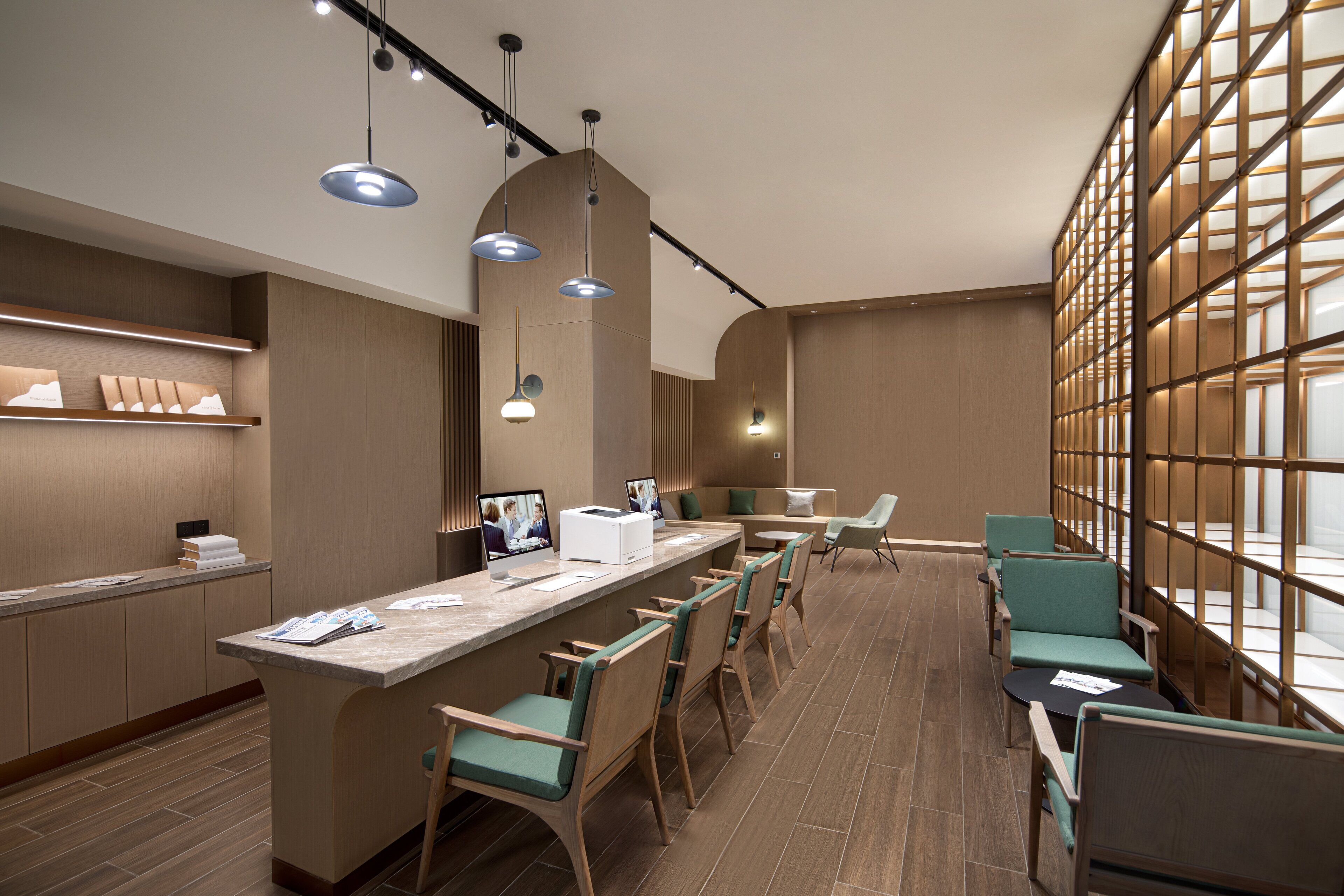 A modern hotel lobby with a reception desk, seating area, and large windows.