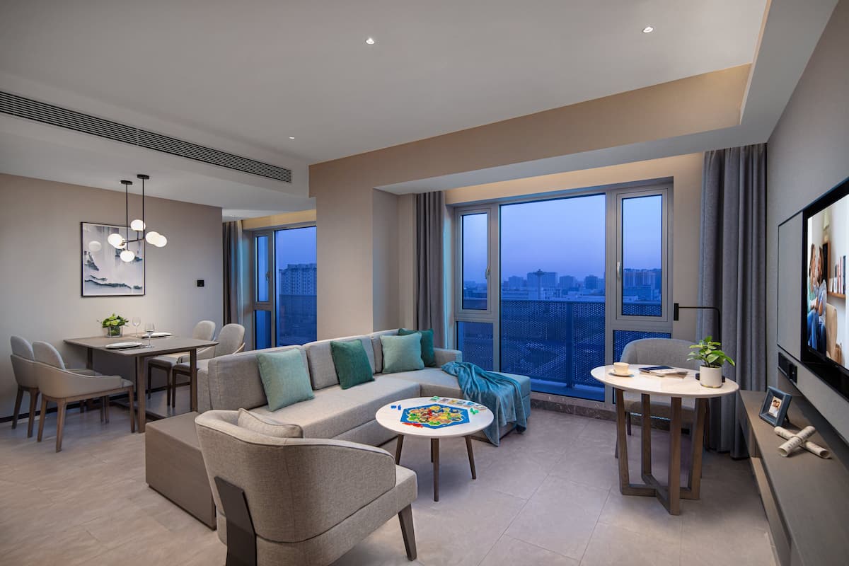 Uma sala de estar moderna com sofá, cadeiras, mesa de jantar e televisão.