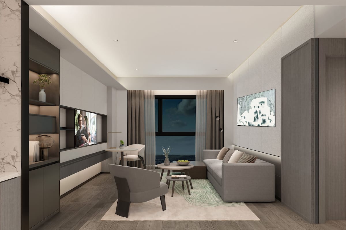Uma sala de estar moderna com sofá, poltrona e mesa de centro, uma TV fixada na parede e uma grande janela com cortinas.