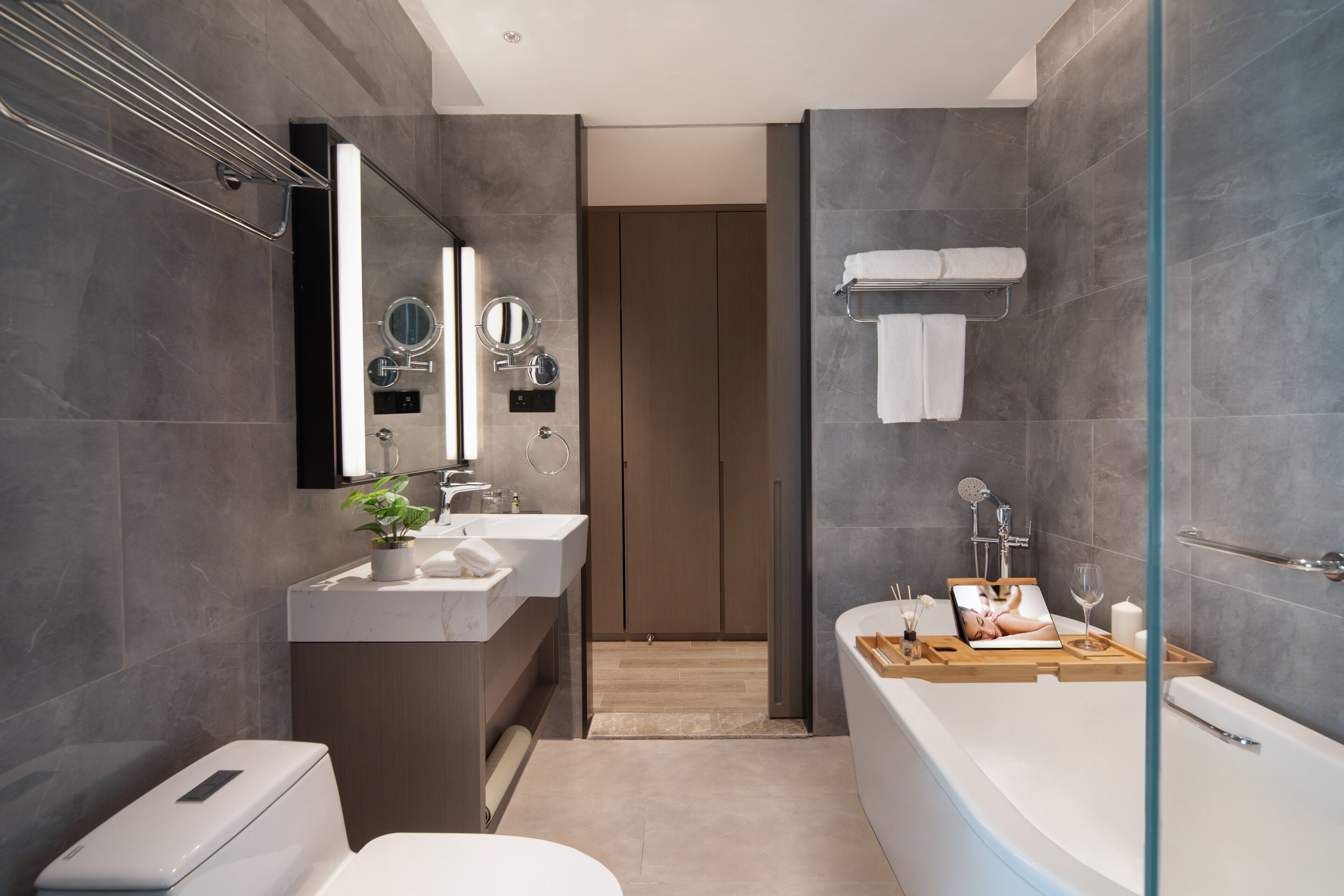 A modern bathroom with a bathtub, a sink, a mirror, and a shower area.