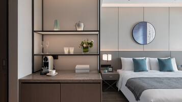 Una habitación de hotel con cama, mesita de noche, lámpara y cafetera.