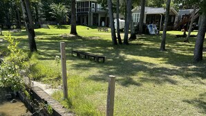 Une promenade au bord de la rivière, dotée d’une terrasse en bois, d’un mur de soutènement en pierre et d’une zone herbeuse avec des tables de pique-nique.