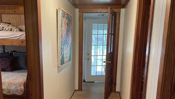 Un couloir étroit, doté de planchers et de murs en bois, qui mène à une porte avec une fenêtre.