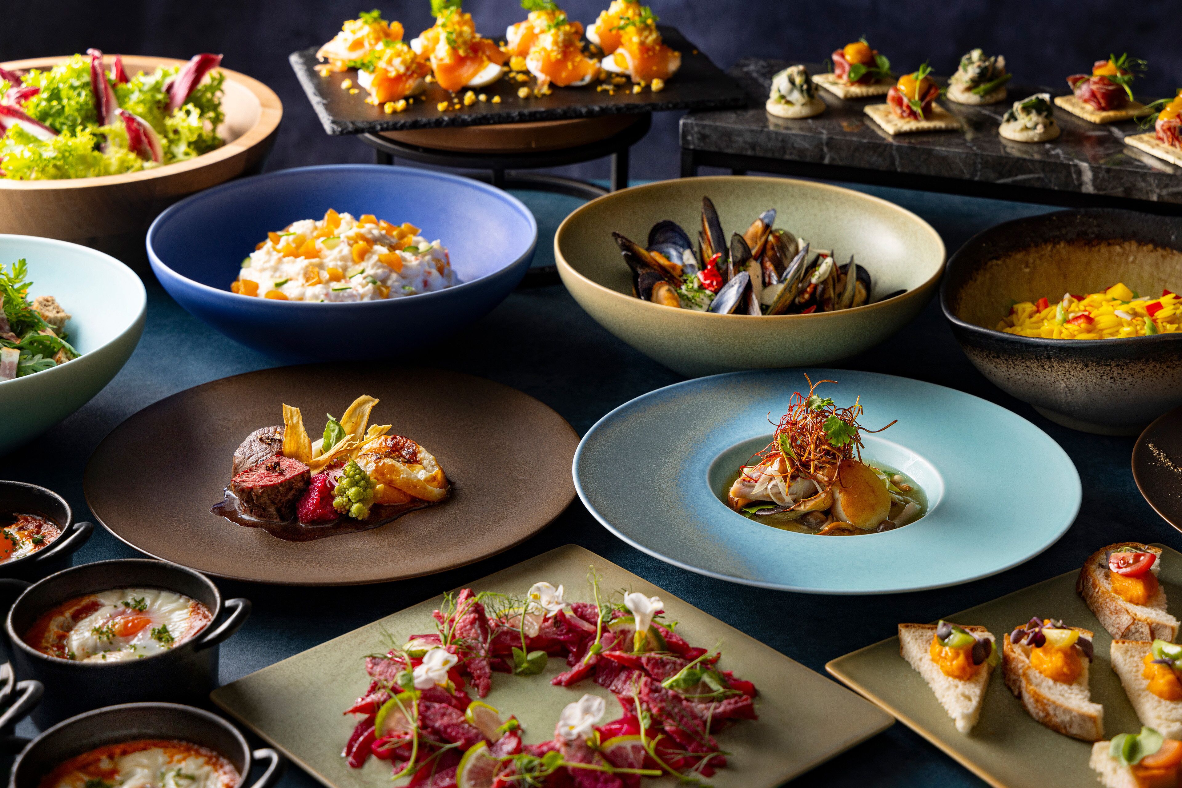 A variety of dishes on a table, including seafood, salads, and appetizers.