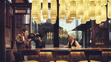 A restaurant with a long table, multiple chairs, and hanging lanterns.