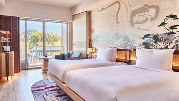 A modern hotel room with two large beds, a balcony with a view, and a large wall mural.