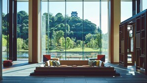 Un interior moderno con ventanas amplias que ofrecen vistas a un jardín exuberante y un edificio tradicional en una colina.