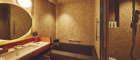 Un baño moderno con un espejo grande, un lavamanos, una bañera y una ducha.
