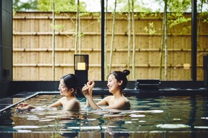 Two people in a hot spring with a bamboo fence in the background. - Hotel Indigo Inuyama Urakuen Garden by IHG (Inuyama)