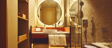 A modern bathroom with a glass shower enclosure, a round mirror, and a sink with a towel rack.