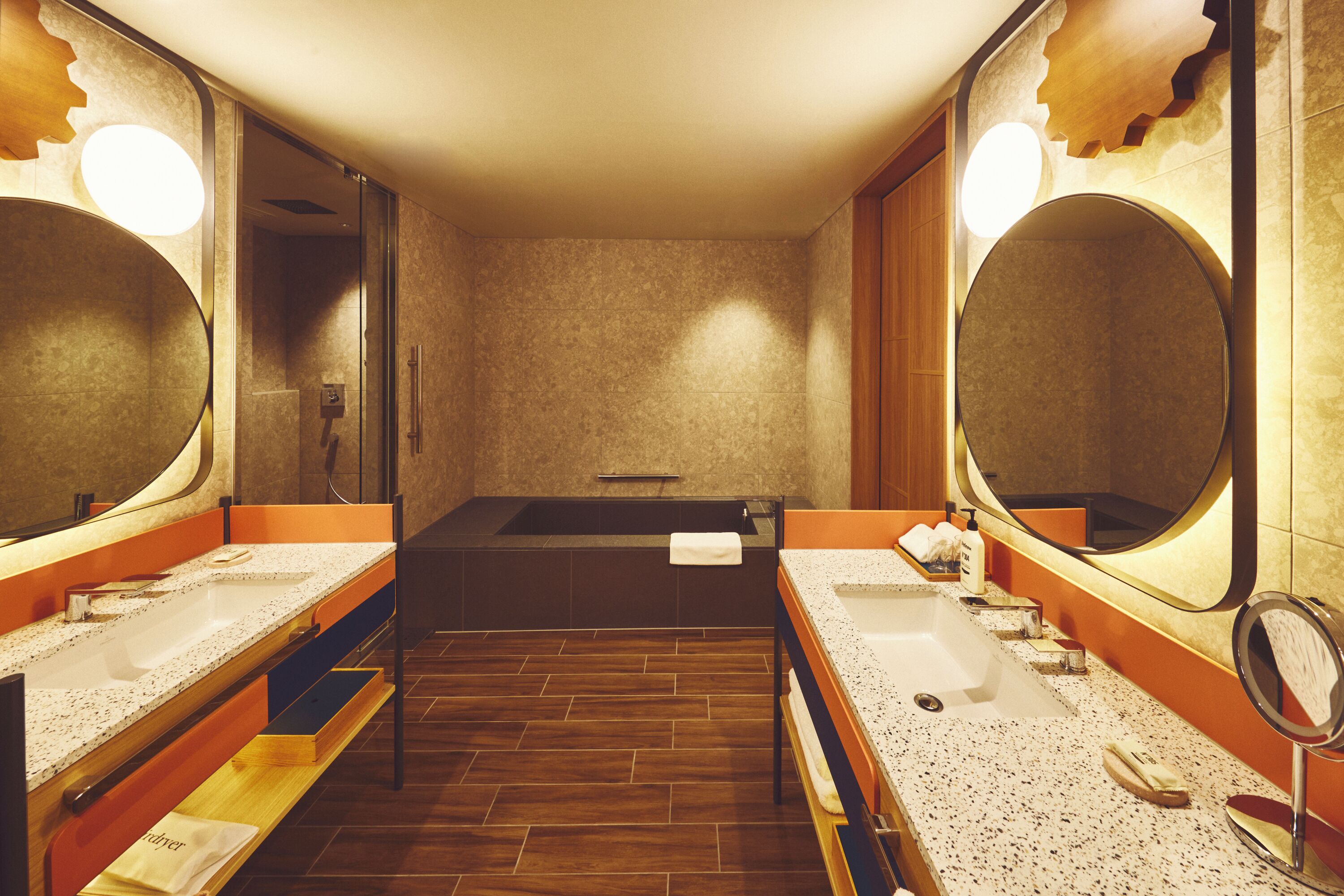 Un baño moderno con dos lavamanos, un espejo grande y una bañera.