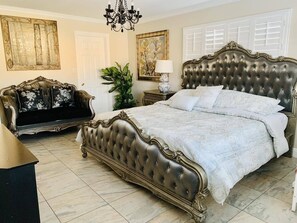 A bedroom with a large bed, a chaise lounge, a chandelier, and a potted plant. - Near Disneyland, Knotts Berry Farm, Beach attractions! (Anaheim)